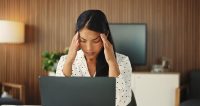 Woman sat at her desk having computer problems. She looks stressed.