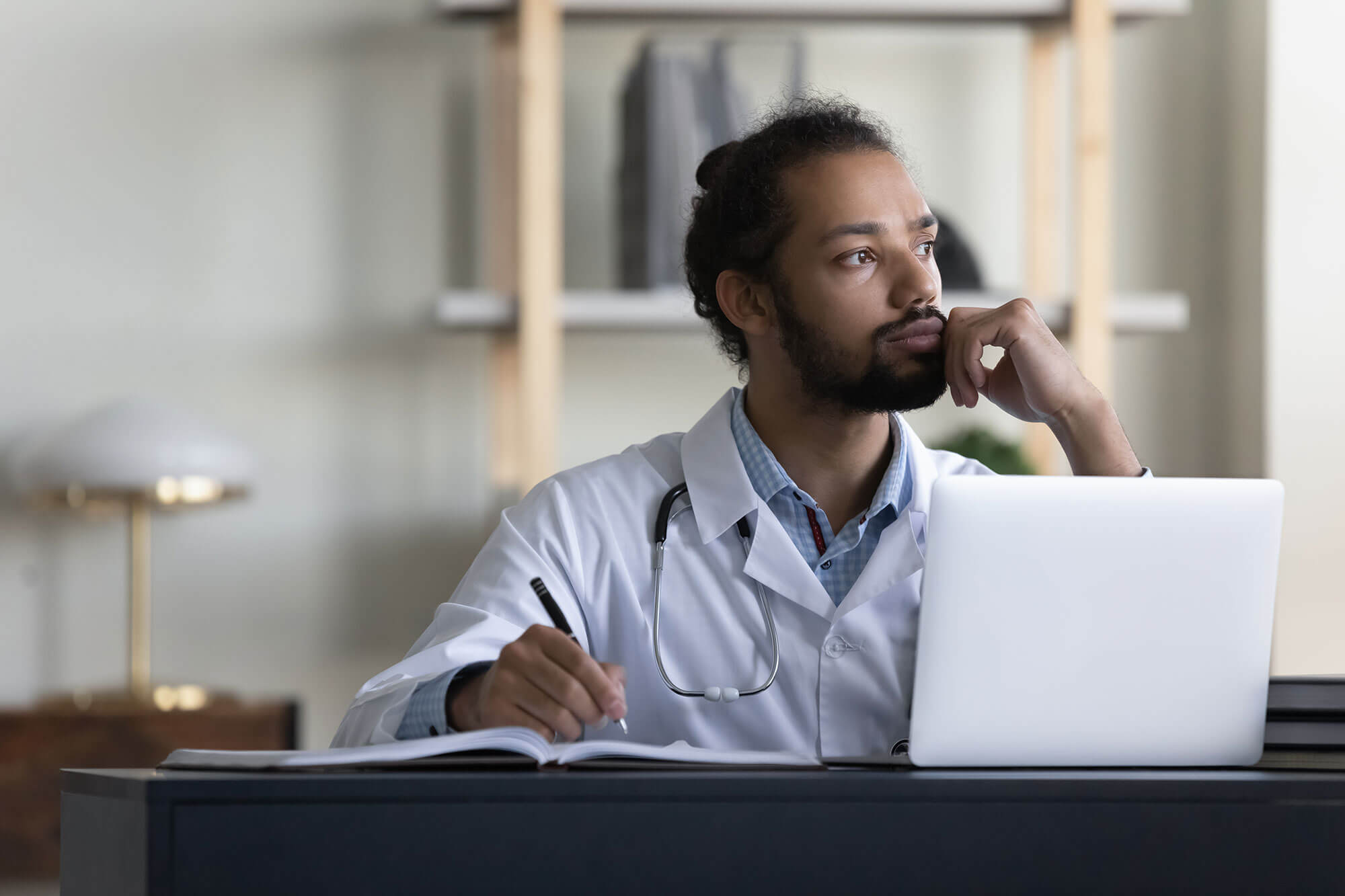 Nurse director sat at laptop while making notes.